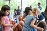 Mehrere Kinder und Erwachsene sitzen gemenisam auf Decken.