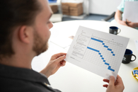 Ein Mitarbeiter hält ein Blatt mit einer statistischen Grafik in der Hand und schaut darauf.