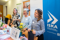 Drei Frauen stehen vor verschiedenen Roll-Ups der ISKA-Einrichtungen und -Projekte.