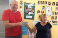 Ein Mann und eine Frau stehe vor einer Zähler-Drehscheibe, der die Zahl 100 anzeigt.