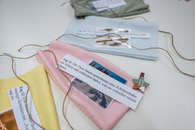 Vier noch leere Säckchen eines Adventskalenders liegen auf einem Tisch. Darauf liegt jeweils ein kleines Foto und ein Papier mit einem Satz aus einer Geschichte, die in die Säckchen gehören.