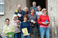 Zu sehen sind die acht Ehrenamtlichen, die teilgenommen hatten, und die Projektleitung. Sie stehen gemeinsam freundlich lächelnd und für das Gruppenfoto posierend vor dem Hintereingang des Freiwilligenzentrums.