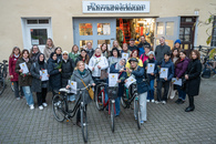 Dreißig Personen, überwiegend Frauen, stehen gemeinsam vor dem Eingang zu einer Fahrradwerkstatt. Viele der Frauen halten eine Teilnehmerurkunde in der Hand, drei der Frauen halten ein Fahrrad fest.