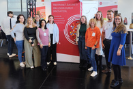 Auf dem Bild stehen Mitarbeitende der Fachdienste Bildungschancen und ISAK zusammen mit Kolleginnen der Kita MOMO vor einem großen ConSozial-Logo.