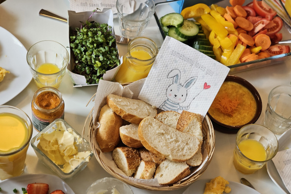 Ein Tisch, lecker gedackt mit Oster-Servietten, Brötchen, Aufschnitten und Orangensaft