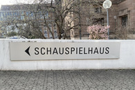 Zu sehen ist der Wegweiser zum Schauspielhaus in Nürnberg an einer Mauer auf dem Areal des Staatstheaters Nürnberg