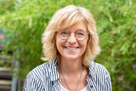 Eine Frau mit mittellangen blonden Haar steht im MOMO-Hof und lächelt in die Kamera.