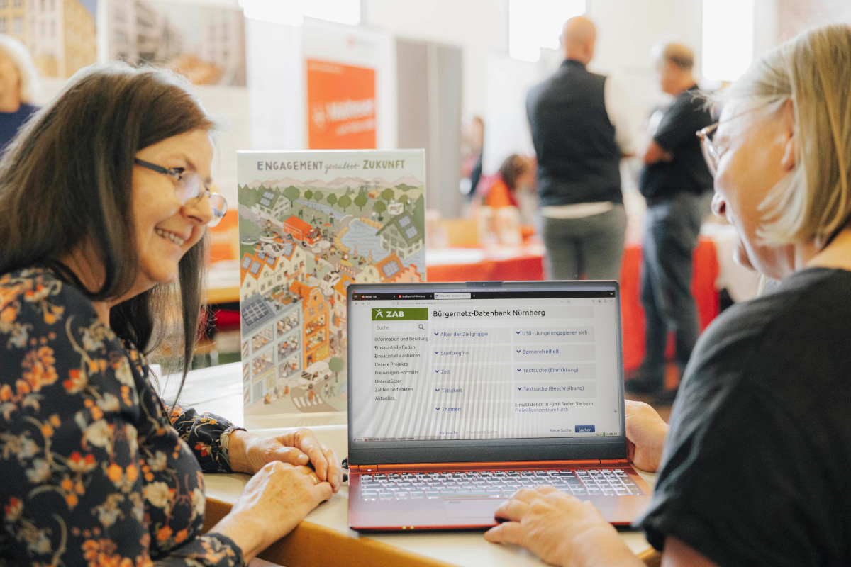 Eine Frau zeigt einer anderen Frau die ZAB-Engagementdatenbank an einem Laptop