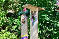 Zwei bemalte Holzstelen mit offenen Mündern.